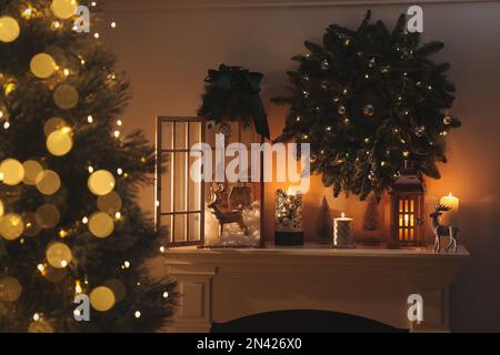 Wunderschöne Holzlaternen, festlicher Kranz und andere Dekorationen im Zimmer mit Weihnachtsbaum Stockfoto