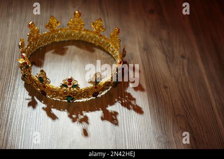 Wunderschöne goldene Krone mit Edelsteinen auf einem Holztisch. Fantasy-Artikel Stockfoto