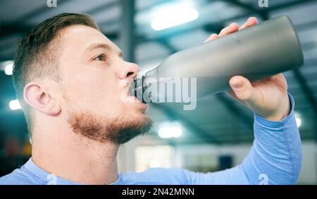 Fitnessstudio, Fitness und Männer trinken Wasser während des Trainings, Training und intensive Kardio, ernsthaft und durstig auf verschwommenem Hintergrund. Hydratation, athletische und Stockfoto