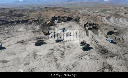 Bagger in Betrieb. Lade Lastwagen auf eine riesige Bergbaustelle. Stockfoto