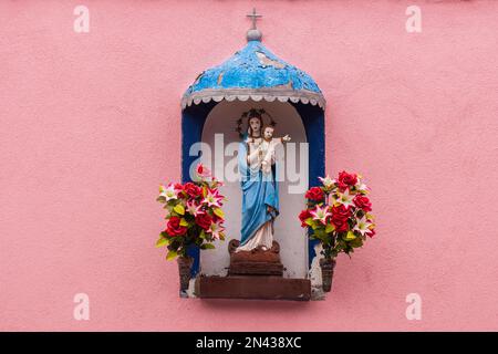 Ein Votivschrein auf einer rosafarbenen Mauer auf der Insel Burano Stockfoto