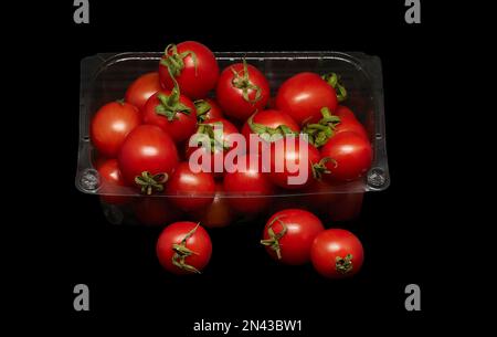 Bild: Kleine Tomaten in Kunststoffverpackung auf schwarzem Hintergrund Stockfoto