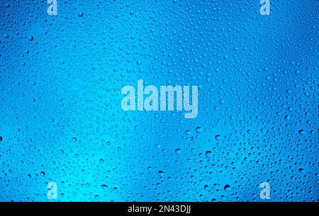 Leuchtender blauer Hintergrund mit kontrastierenden Wassertropfen. Stockfoto