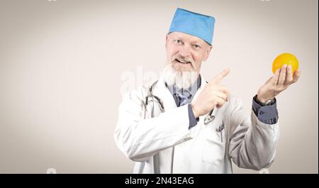 Ein älterer Arzt mit einem lächelnden Bart empfiehlt, Orangen zu essen. Stockfoto