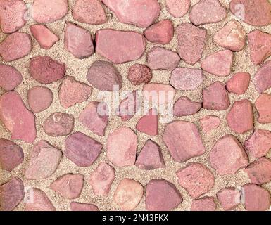 Textur roter Flusssteine im Sand. Stockfoto