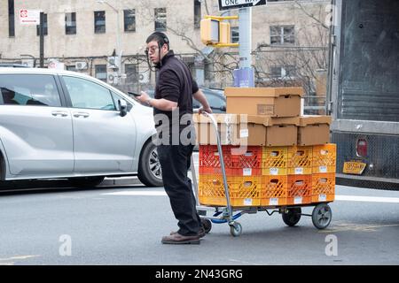 Ein Arbeiter für Satmar Meat liefert Kisten und Kartons vom Lager zu einem der Geschäfte. In Brooklyn, New York. Stockfoto