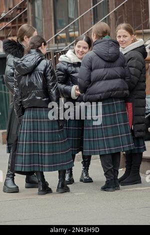 Chassidische jüdische Mädchen, die die Schuluniform tragen, halten für ein Gespräch auf dem Heimweg an. Sie tragen bescheidene, lange Karomöcke. In Brooklyn, New Yor. Stockfoto