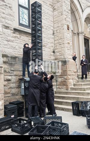 Ultraorthodoxe jüdische Jeschiva-Schüler in einer städtischen Schule bauen während ihrer Pause einen Turm aus Milchkisten. In New York City. Stockfoto