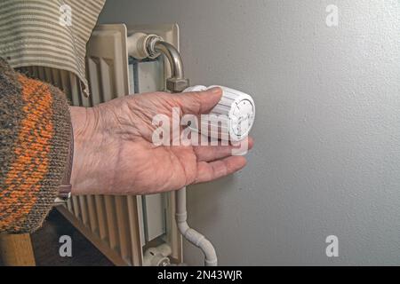 Nahaufnahme der Hand mit Heizkörperthermostat, Heizkörper und Thermostat in flacher Heizung Stockfoto
