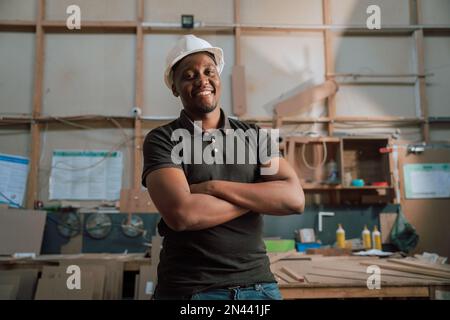 Afrikanischer männlicher glücklicher, zuversichtlicher Trainee Zimmermann Vorgesetzter bei der Arbeit in der Fabrik Stockfoto