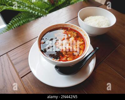 Asiatische Küche – Kimchi-Suppe in einer weißen Schüssel mit Reis. Nahaufnahme des Fotos. Stockfoto