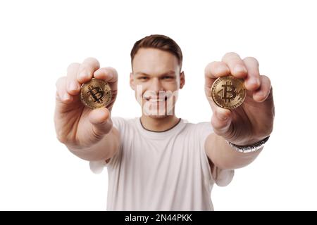 Ein Mann hält Bitcoin-Münzen in ausgestreckten Händen. Stockfoto