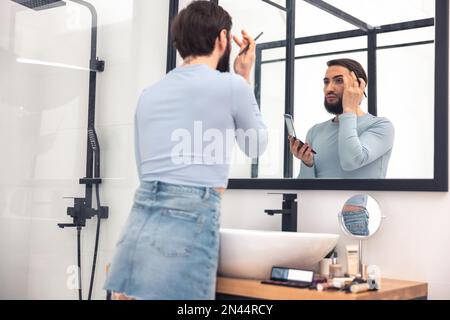 Ein Mann, der sich während der Make-up-Anwendung ansieht Stockfoto