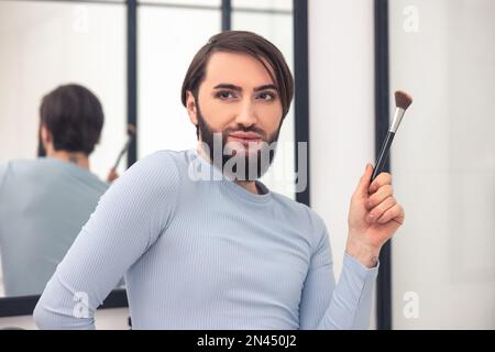 Junger Mann träumt während der Make-up-Anwendung Stockfoto