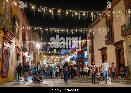 Im historischen Oaxaca, Mexiko, feiern die Massen die Weihnachtszeit unter der Dekoration der Calle Macedonio Alcala bei Nacht. Stockfoto