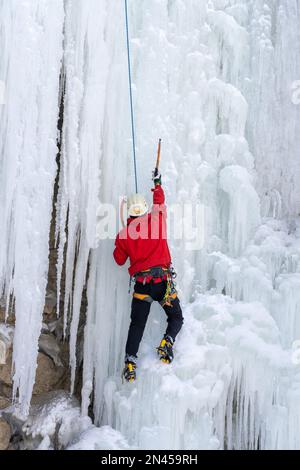 Ein Eiskletterer auf einem natürlichen gefrorenen Wasserfall im Price Canyon in Utah. Stockfoto