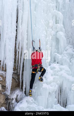 Ein Eiskletterer auf einem natürlichen gefrorenen Wasserfall im Price Canyon in Utah. Stockfoto