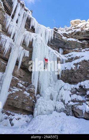 Ein Eiskletterer auf einem natürlichen gefrorenen Wasserfall im Price Canyon in Utah. Stockfoto