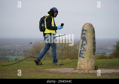 Ein Mitarbeiter des Büros für öffentliche Arbeiten filmt die Graffiti auf dem Lia Fail Standing Stone, auch bekannt als der Stein des Schicksals, auf dem Hügel von Tara bei Skryne in County Meath. Bilddatum: Mittwoch, 8. Februar 2023. Stockfoto