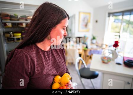 Essen aus dem Kühlschrank holen. Bier im Kühlschrank. Kühlschrank voller Essen. Gefrierschrank voll mit Essen. Eine Person, die entscheidet, was sie zum Abendessen von einem Freund essen Stockfoto
