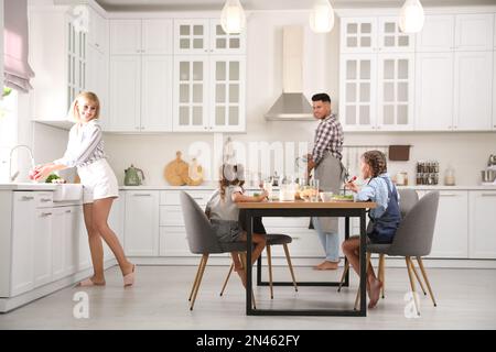 Glückliche Familie, die zusammen am Tisch in der modernen Küche frühstückt Stockfoto