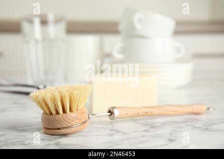 Reinigungsbürste zum Geschirrspülen auf weißem Marmortisch in Innenräumen, Nahaufnahme Stockfoto