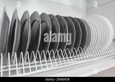 Trockengestell mit sauberen Platten im Küchenschrank, Nahaufnahme Stockfoto