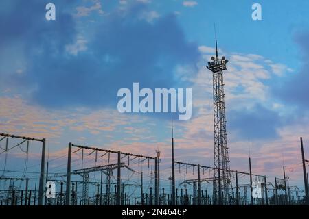 Moderne elektrische Unterstation gegen bewölkten Himmel bei Sonnenuntergang Stockfoto