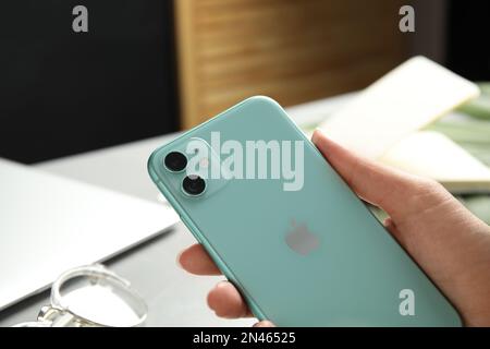 MYKOLAIV, UKRAINE - 9. JULI 2020: Frau mit iPhone 11 Green am Tisch, Nahaufnahme Stockfoto