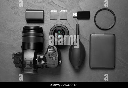 Flachlagenkomposition mit Kamera- und Videoproduktionsausrüstung auf grauem Steinhintergrund Stockfoto