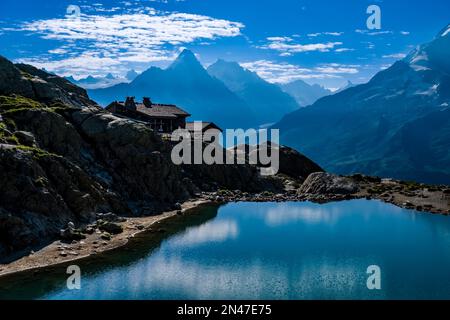 Die Berghütte Refuge du Lac Blanc am See Lac Blanc, die Gipfel von Aiguille d'Argentiere und Aiguille de Chardonnet in der Ferne. Stockfoto