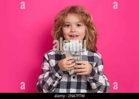 Ein Kind, das viele hundert Dollar isoliert auf rosa rotem Hintergrund hat. Stockfoto
