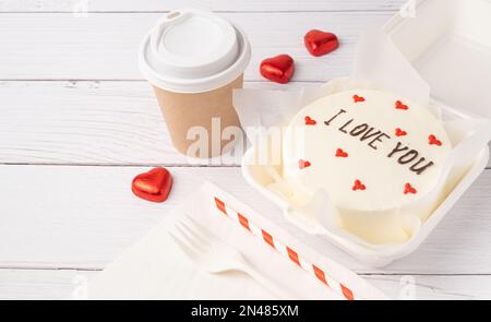 Kleiner Bento-Kuchen im Karton auf weißem Holzhintergrund Stockfoto