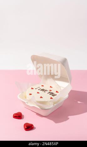 Kleiner Bento-Kuchen im Karton auf minimalistischem Hintergrund Stockfoto