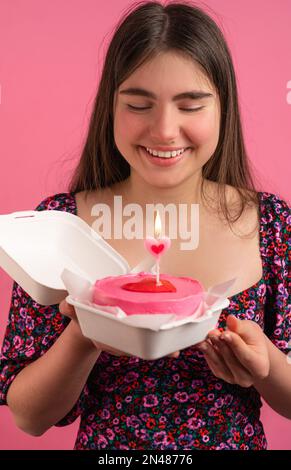 Mädchen mit Bento-Kuchen und Blume auf pinkfarbenem Hintergrund Stockfoto
