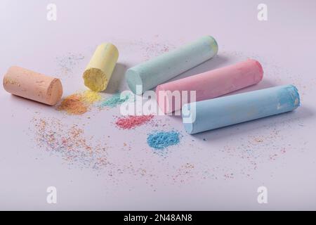Zylindrische farbige Kreiden, teilweise zerbröselt, auf weißem Hintergrund Stockfoto