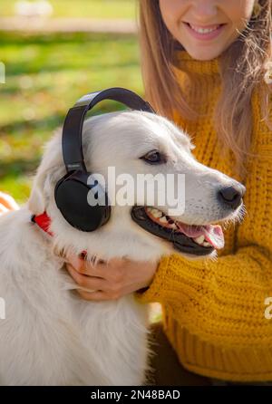 Belgrad, Serbien. 10. November 2022. Ein Mädchen lächelt mit ihrem Hund und hört Musik über Kopfhörer Stockfoto