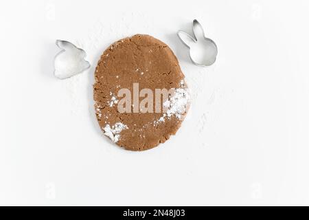 Roher osterkuchen-Teig mit Schneidemehl und Mehl. Zubereitung von Osterkeksen. Weißer Hintergrund Stockfoto