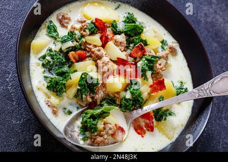 Nahaufnahme von Zuppa Toscana, einer herzhaften toskanischen Suppe mit italienischer Wurst, Grünkohl, gebratenem Speck und Kartoffeln in einer schwarzen Schüssel Stockfoto