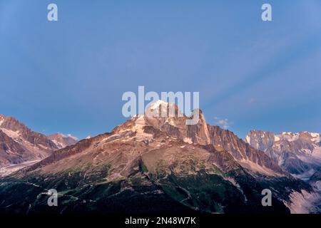 Die Gipfel von Aiguille Verte und Grand Dru, der aufgehende Mond dahinter zeichnet ein Muster am Himmel. Stockfoto