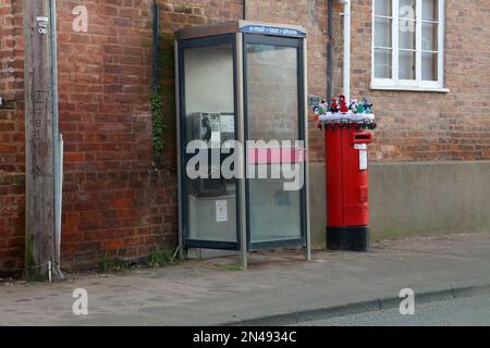 Ein ziemlich seltsames Set aus Strickspielzeug auf einer Säulenbox neben einer öffentlichen Telefonzelle in der Old Street Upton Upon Severn. Stockfoto