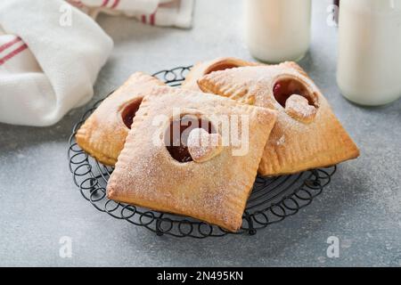 Valentinstag herzförmige Handkuchen. Mini-Blätterteig oder Handkuchen gefüllt mit Apfel und streuen Sie Zuckerpulver auf den Teller. Eine Idee für hausgemachte Romantiker Stockfoto