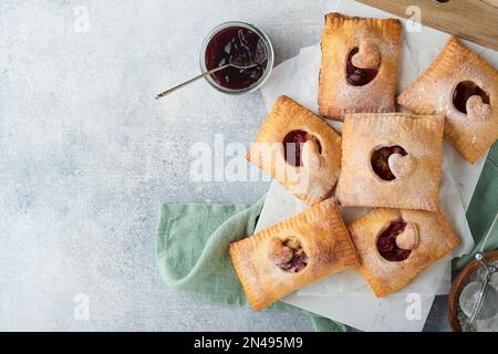 Valentinstag herzförmige Handkuchen. Mini-Blätterteig oder Handkuchen gefüllt mit Apfel und streuen Sie Zuckerpulver auf den Teller. Eine Idee für hausgemachte Romantiker Stockfoto