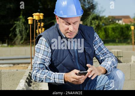 Leitender Ingenieur mit Smartphone auf der Baustelle Stockfoto