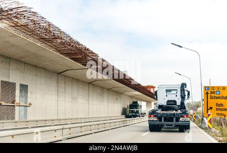 Österreich - 30. Sept. 2014: Rückansicht eines weißen Mercedes-Benz-Lkws, der schnell auf der österreichischen Autobahn neben einer Baubrücke aus Stahlstangen und Beton fährt Stockfoto