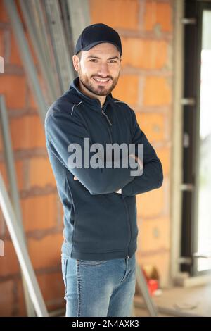 Fröhlicher Baumeister, der auf der Baustelle lächelt Stockfoto