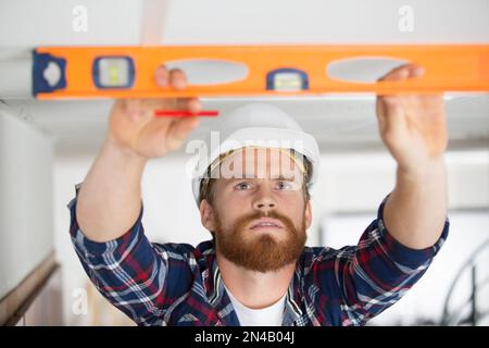 Männlicher Bauunternehmer mit Wasserwaage Stockfoto