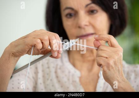 Reife Frau fängt an zu stricken Stockfoto