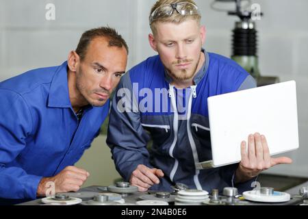 Arbeiter in Blau, die den Laptop überprüfen Stockfoto