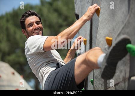 Attraktiver junger Mann, der im Freien Felsklettern oder Felsklettern kann Stockfoto